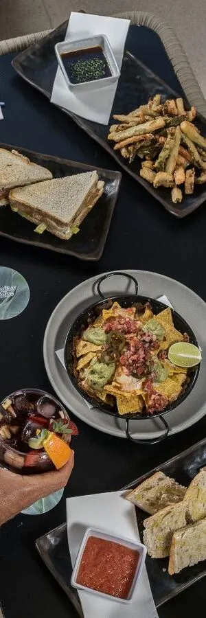 Platos variados con nachos, bocadillos y bebida sobre una mesa negra.